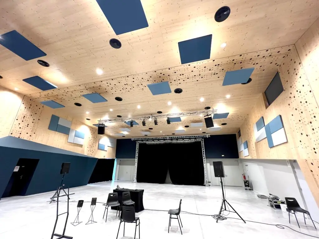 Salle de conservatoire de musique moderne, dotée de panneaux acoustiques muraux et de diffuseurs sonores pour optimiser l’acoustique. Des instruments de musique sont disposés dans la pièce où l’aménagement acoustique favorise une excellente qualité sonore, idéale pour la pratique musicale et les répétitions.
