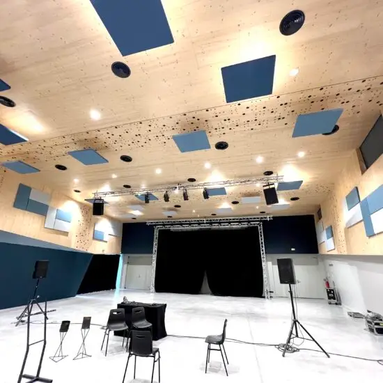 Salle de conservatoire de musique moderne, dotée de panneaux acoustiques muraux et de diffuseurs sonores pour optimiser l’acoustique. Des instruments de musique sont disposés dans la pièce où l’aménagement acoustique favorise une excellente qualité sonore, idéale pour la pratique musicale et les répétitions.